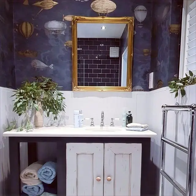 Dark floral wallpaper, a gold-framed mirror and a grey vanity.